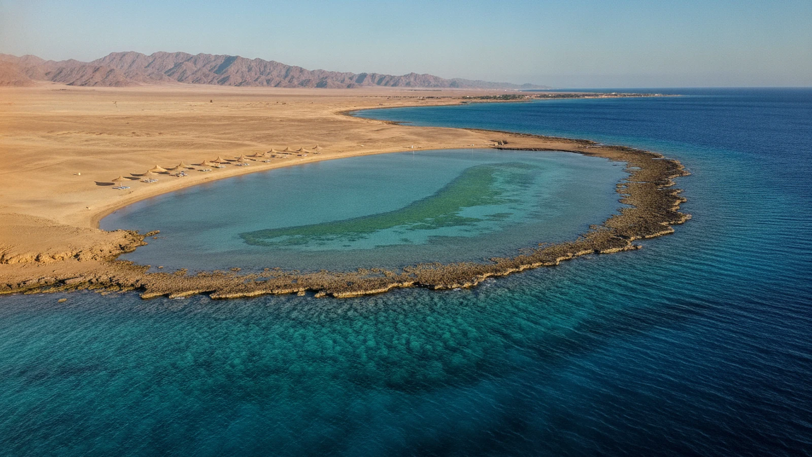 Písčitá zátoka u Marsa Alam s pásem mořské trávy uprostřed a korálovým útesem po stranách