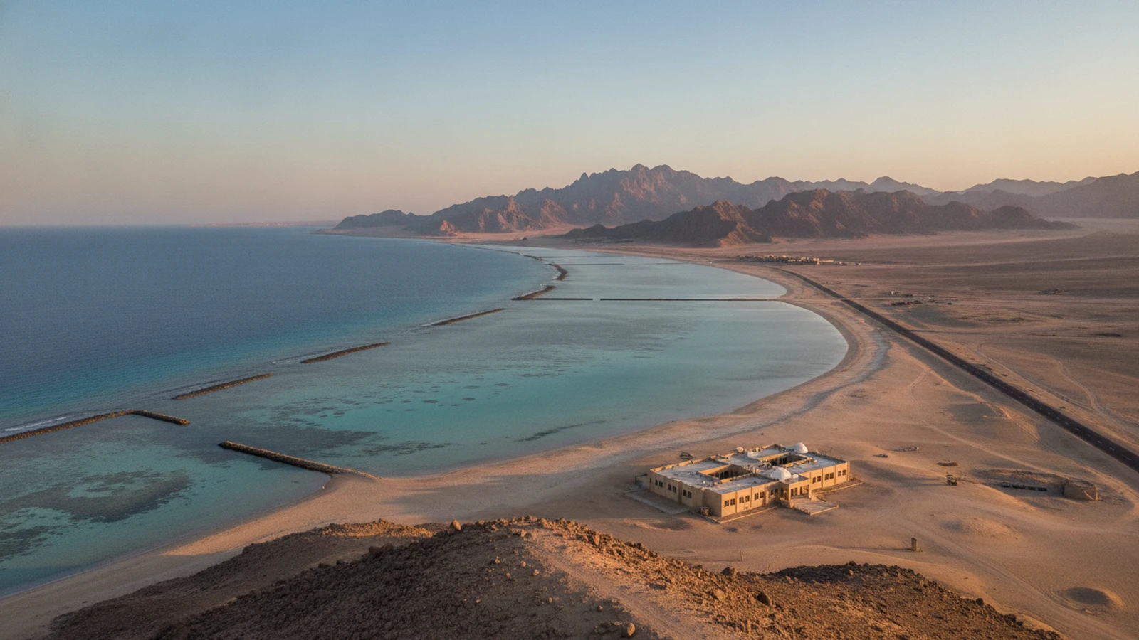 Záliv u Marsa Alam s mělkou tyrkysovou vodou, osamělým resortem v poušti a horami Východní pouště