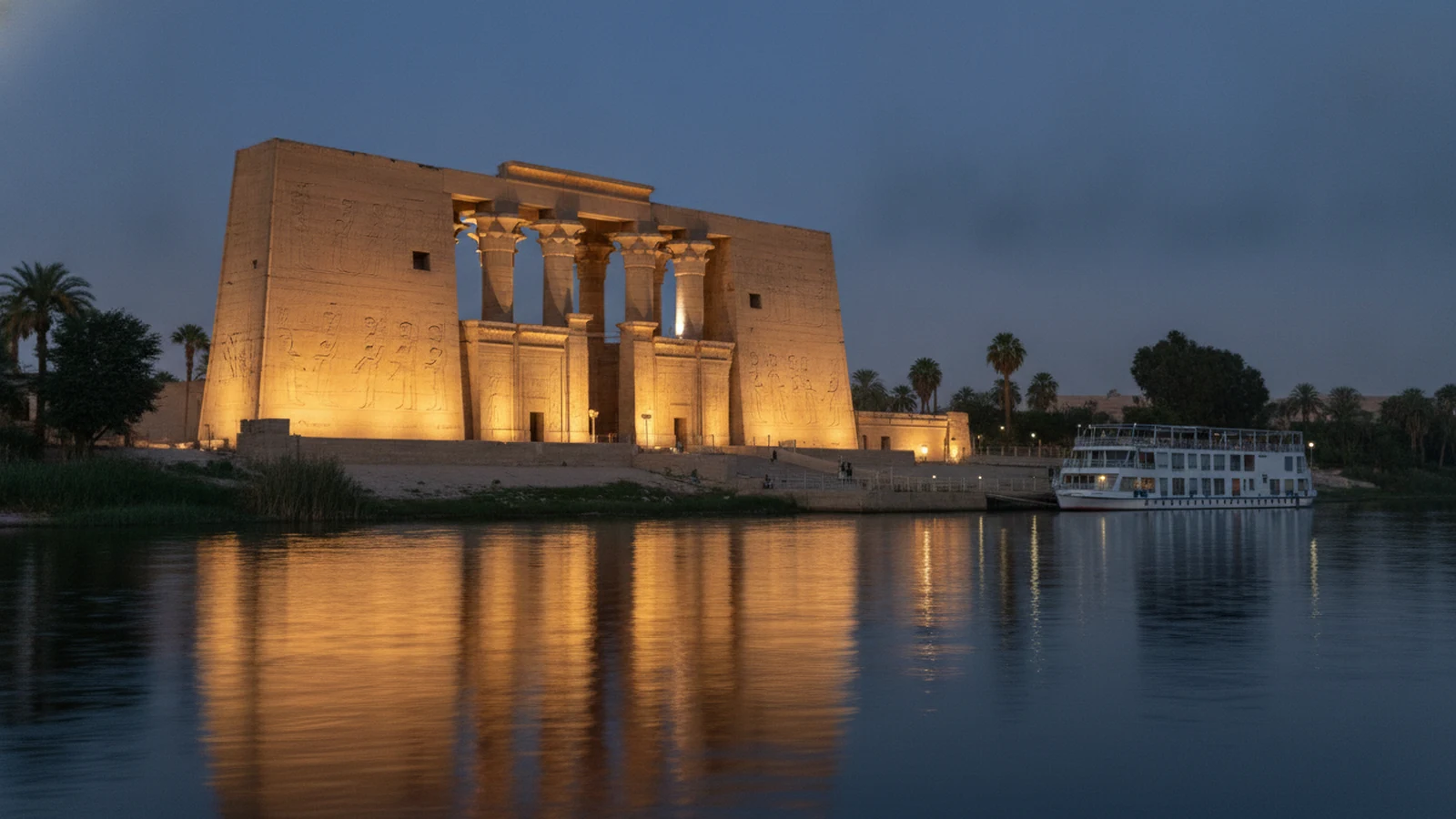 Výletní loď kotví na Nilu pod chrámem Kom Ombo za soumraku