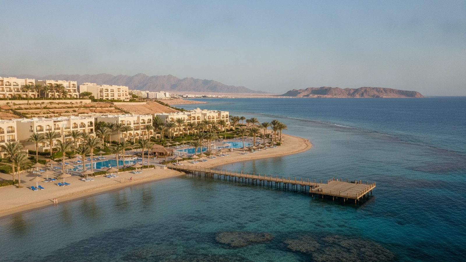 All inclusive resort v Šarm aš-Šajchu s bazény, palmami a dřevěným molem nad korálovým útesem