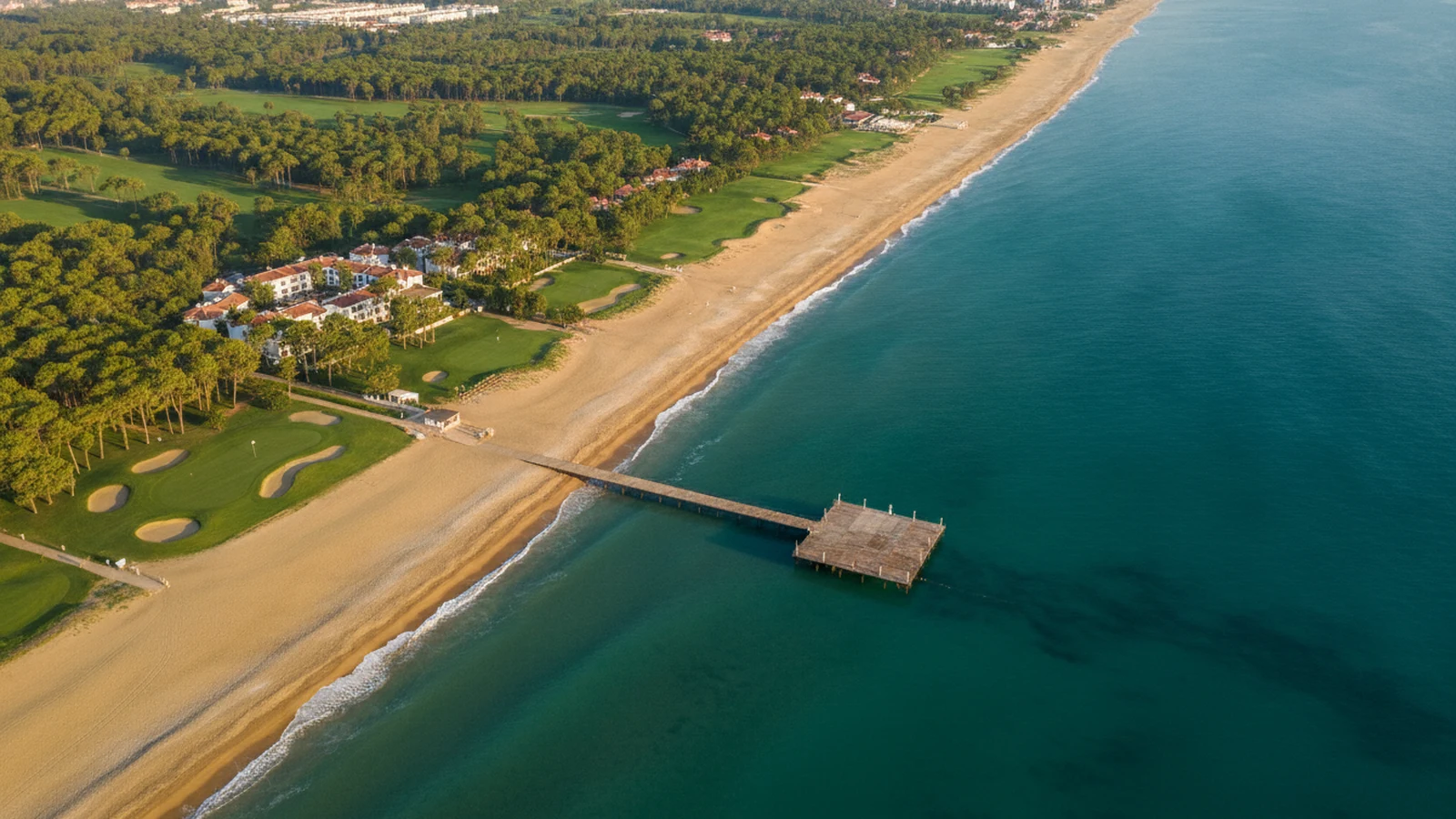 Pobřeží Beleku s písečnou pláží, borovým lesem a golfovým hřištěm za resorty