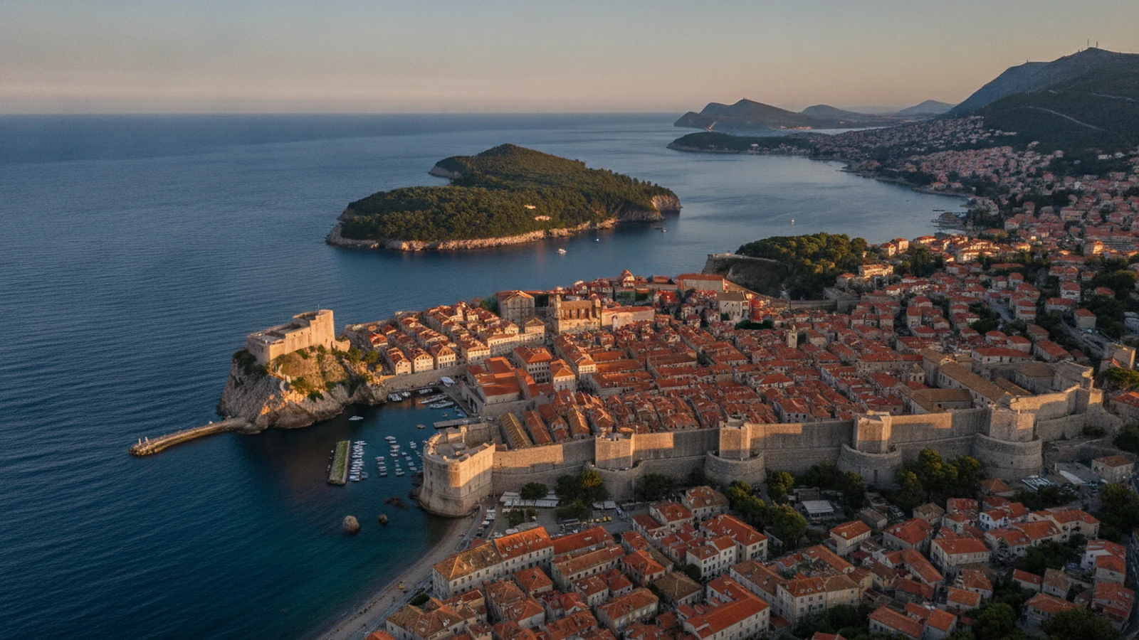 Hradby a střechy Starého města v Dubrovníku s pevností Lovrijenac a ostrovem Lokrum za jasného rána