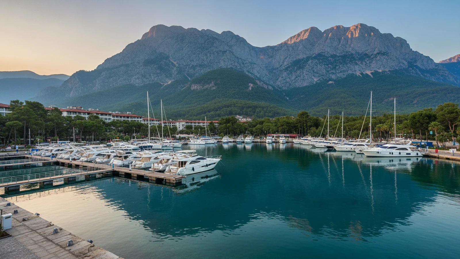 Marina v Kemeru s jachtami, nízkými hotely mezi borovicemi a horami Beydağları v pozadí