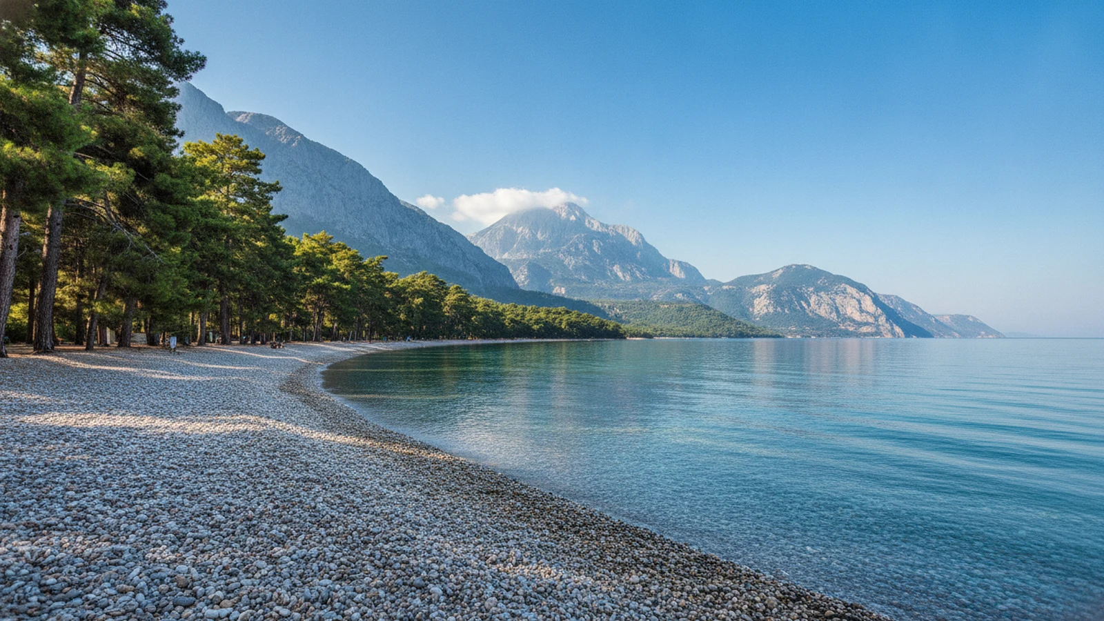 Oblázková pláž v Kemeru s borovicemi a horami Beydağları v pozadí