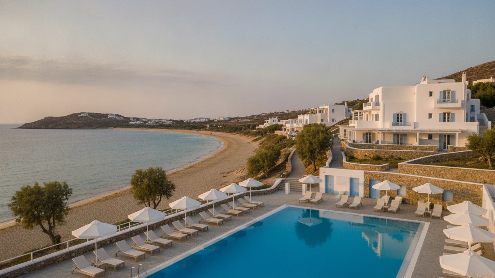 Nízký bílý kykladský hotel s bazénem ve svahu nad pláží Agios Prokopios na Naxu