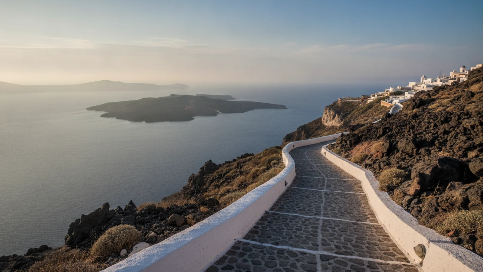 Kamenná stezka po hraně kaldery mezi Imerovigli a Oiou na Santorini s výhledem na sopečný ostrůvek Nea Kameni