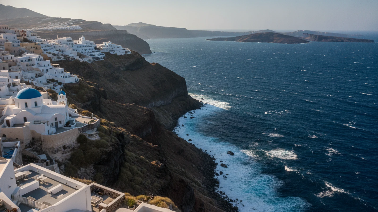Bílé domy na hraně kaldery v Imerovigli na Santorini nad zvlněným Egejským mořem